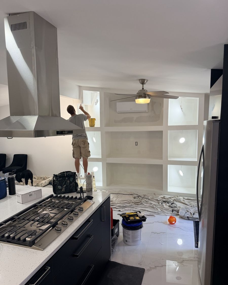 Crew member on a ladder painting built-in shelving, with drop cloths covering the floor.