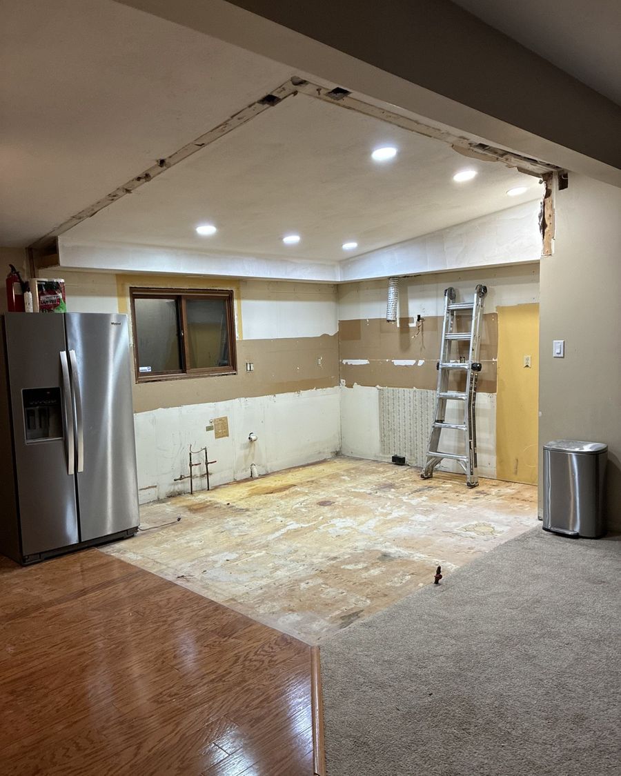 Kitchen with cabinets removed and flooring stripped to the subfloor.